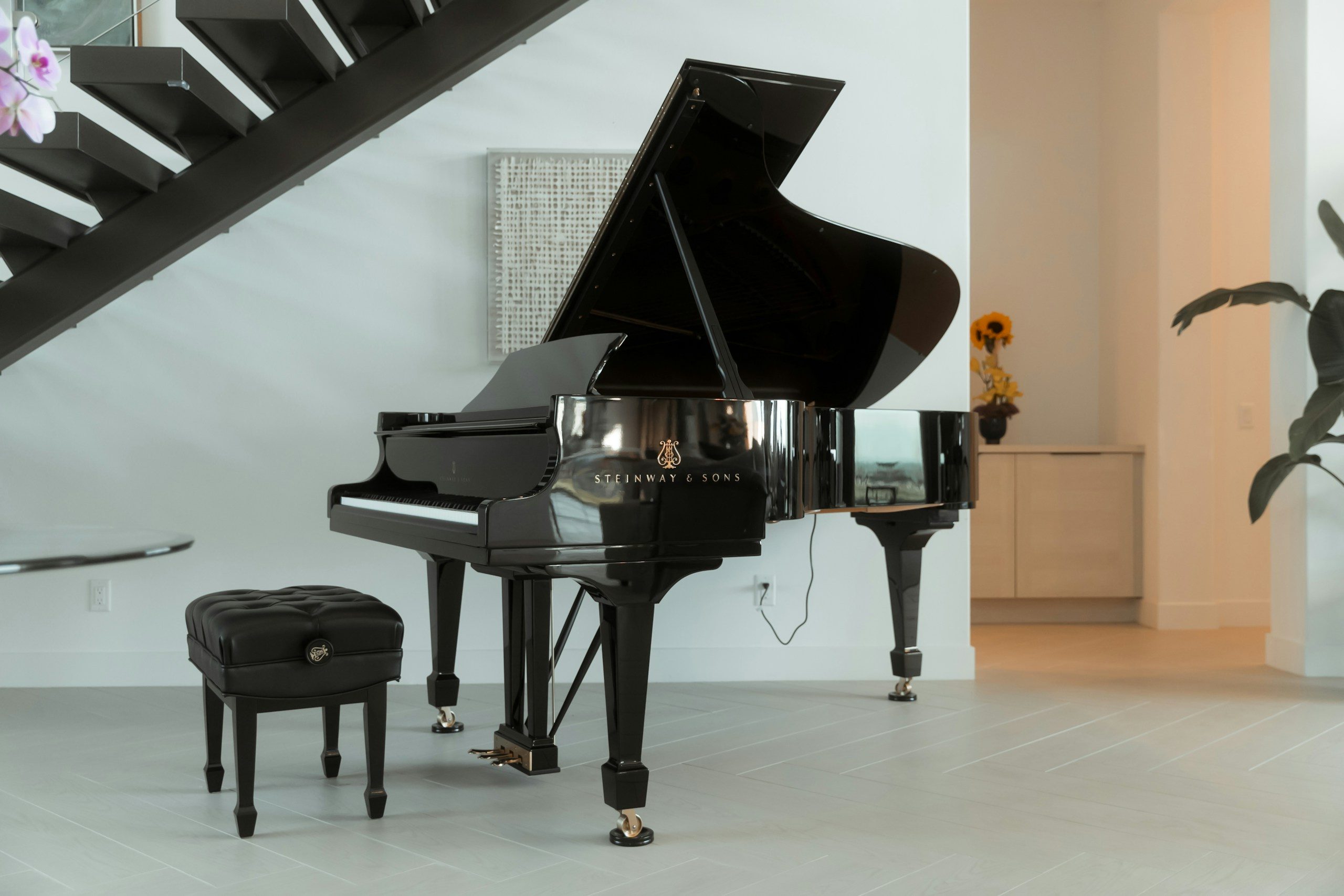 Grand piano at the foot of a staircase in a modern home, the kind of access that affects how much piano movers cost